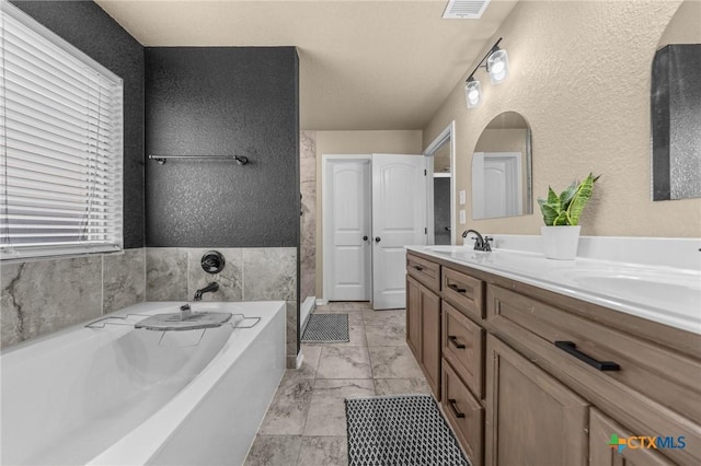 1442 Neff Dr, Copperas Cove, TX 76522 - full bathroom with a textured wall, a garden tub, double vanity, and marble look tiles