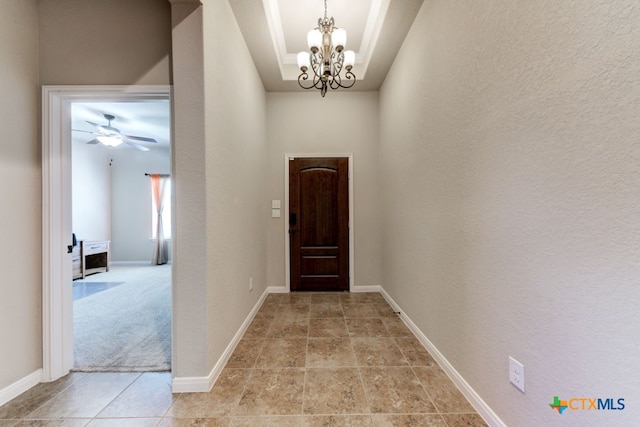 hallway with light colored carpet and a notable chandelier