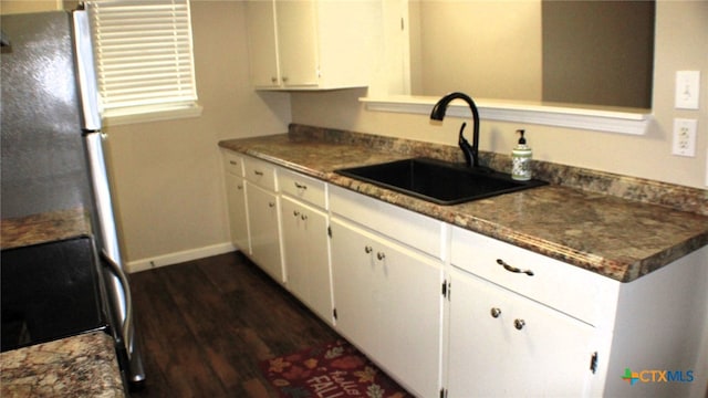 kitchen with white cabinets, sink, dark hardwood / wood-style floors, black stove, and dark stone countertops