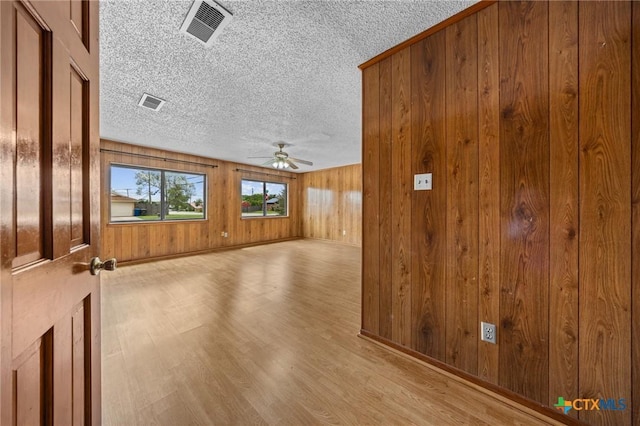 101 E Hogan Dr, Copperas Cove, TX 76522 - unfurnished room featuring ceiling fan, wood finished floors, a textured ceiling, and wooden walls