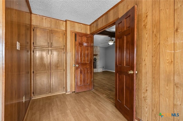 101 E Hogan Dr, Copperas Cove, TX 76522 - corridor with wooden walls, light wood-style flooring, crown molding, and a textured ceiling