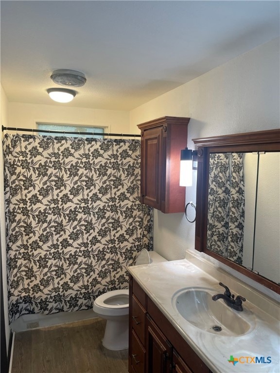 bathroom featuring toilet, vanity, hardwood / wood-style flooring, and curtained shower