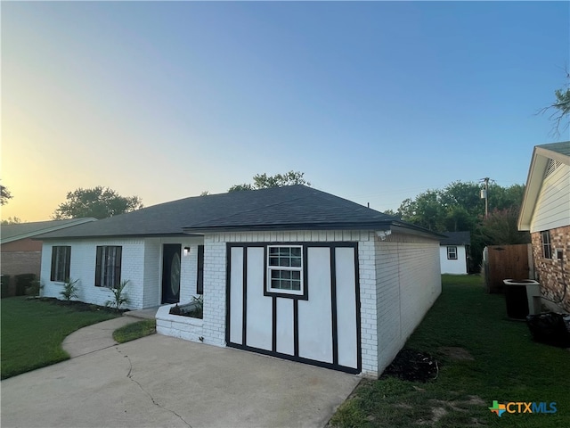 view of front of home with central air condition unit, a lawn, and a patio