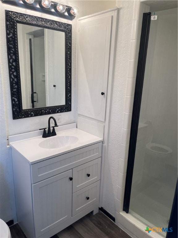 bathroom featuring walk in shower, hardwood / wood-style floors, and vanity