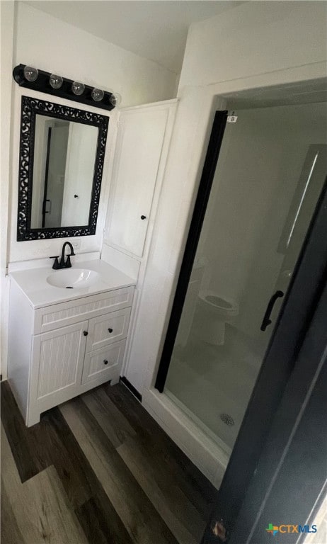 bathroom with walk in shower, hardwood / wood-style floors, and vanity