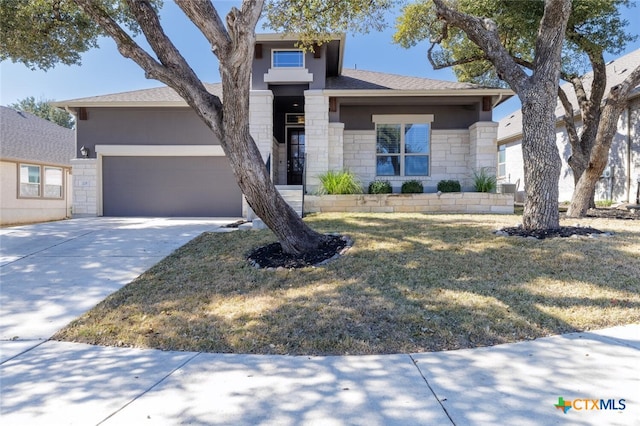 view of front of property featuring an attached garage, stone siding, concrete driveway, stucco siding, and a front lawn