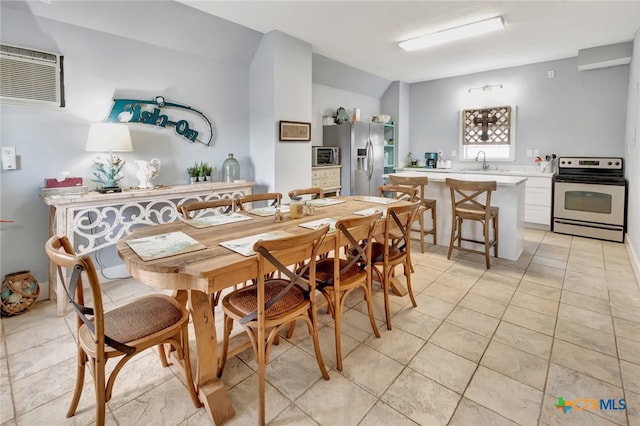 dining area featuring sink, light tile patterned floors, a wall mounted AC, and vaulted ceiling