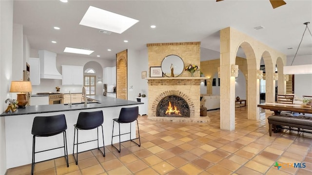 680 Saddleridge Dr, Wimberley, TX 78676 - kitchen featuring dark countertops, a sink, high end stove, white cabinetry, and custom exhaust hood
