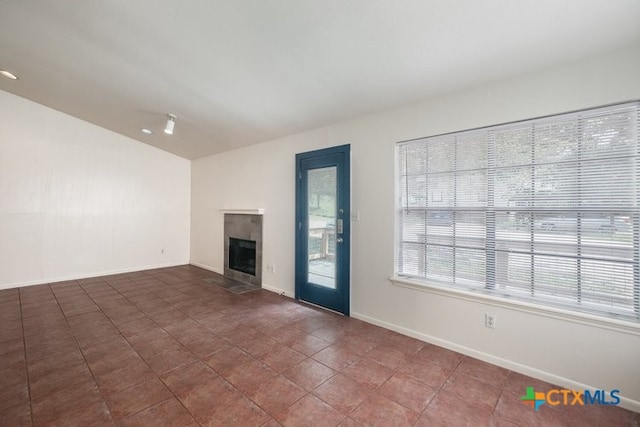 1102/1104/1106 Academy St, San Marcos, TX 78666 - unfurnished living room featuring a tiled fireplace, tile patterned floors, baseboards, and vaulted ceiling