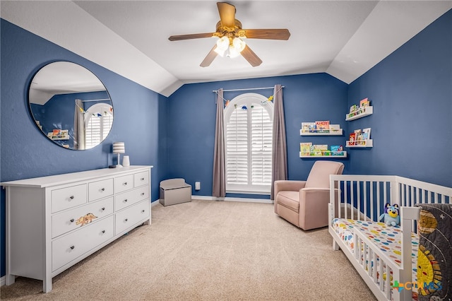 bedroom featuring vaulted ceiling, a nursery area, light colored carpet, and ceiling fan