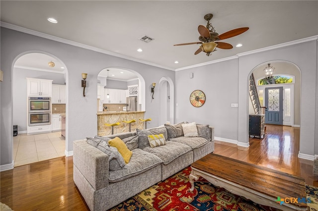 living room featuring ornamental molding, ceiling fan, and light hardwood / wood-style flooring