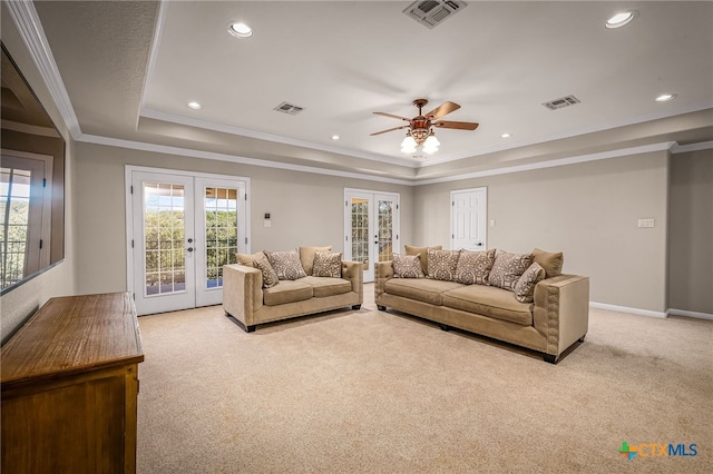 carpeted living room with ornamental molding, a tray ceiling, ceiling fan, and french doors