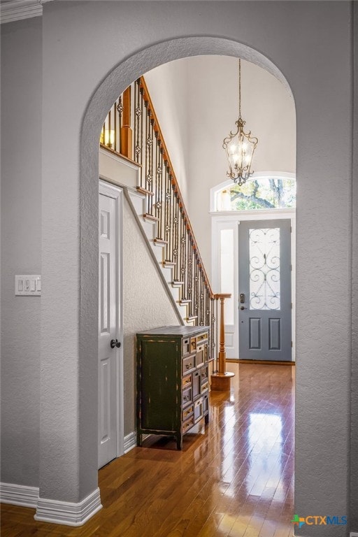 entryway featuring hardwood / wood-style flooring, an inviting chandelier, and a high ceiling