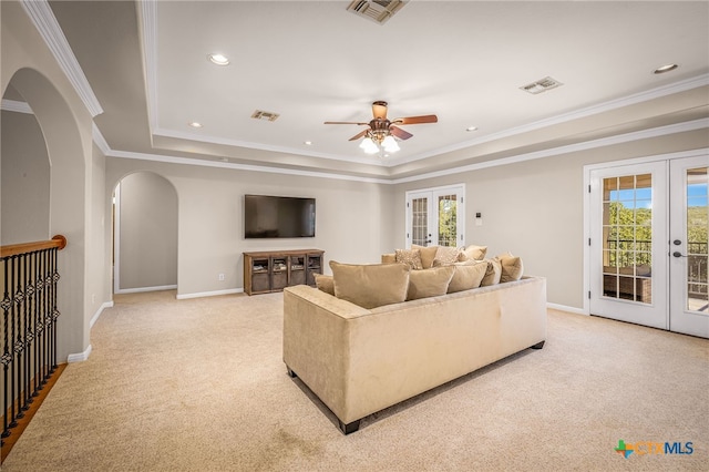 living room with light carpet, ornamental molding, french doors, and a raised ceiling