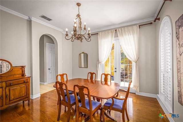 dining area with an inviting chandelier, ornamental molding, and light hardwood / wood-style floors