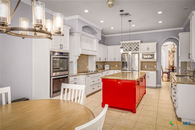 kitchen with decorative light fixtures, dark stone countertops, a kitchen island, stainless steel appliances, and white cabinets