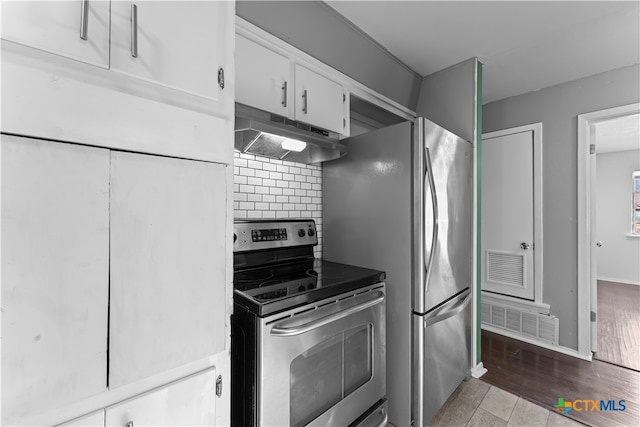 kitchen with backsplash, white cabinets, stainless steel appliances, and light hardwood / wood-style floors