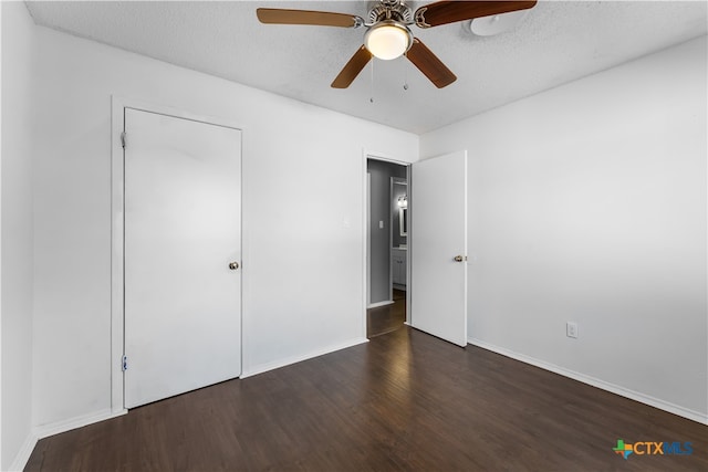 unfurnished bedroom featuring ceiling fan, a closet, dark wood-type flooring, and a textured ceiling