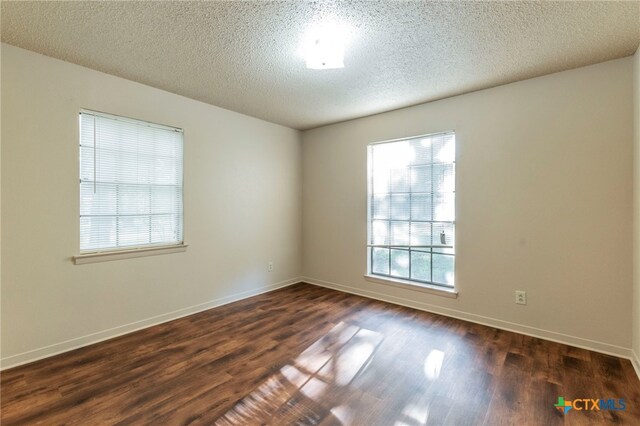 202 Liberty St, Gatesville, TX 76528 - unfurnished room featuring dark wood-type flooring, baseboards, and a textured ceiling