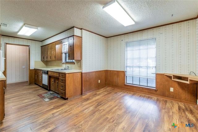 202 Liberty St, Gatesville, TX 76528 - kitchen with light wood-style floors, light countertops, brown cabinets, a textured ceiling, and ornamental molding
