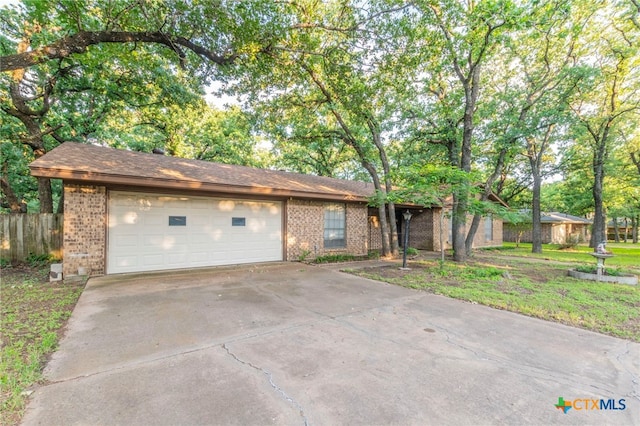 202 Liberty St, Gatesville, TX 76528 - view of front of house with brick siding, concrete driveway, an attached garage, and fence
