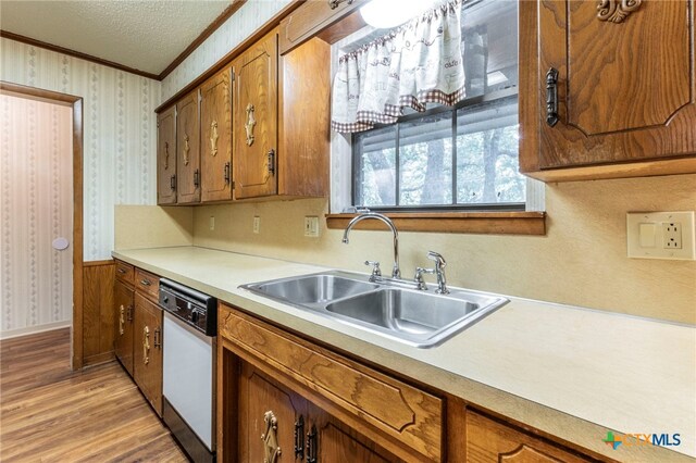 202 Liberty St, Gatesville, TX 76528 - kitchen featuring a sink, white dishwasher, ornamental molding, brown cabinets, and light wood-type flooring