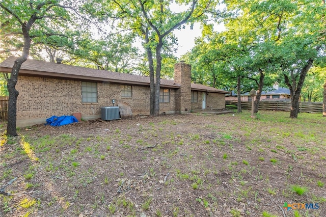 202 Liberty St, Gatesville, TX 76528 - rear view of property featuring fence, a chimney, central AC, and brick siding