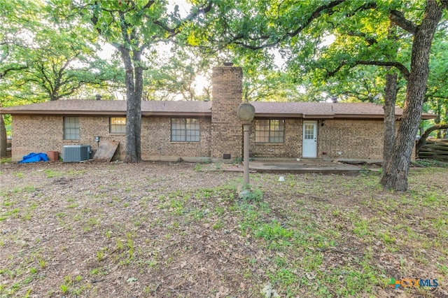 202 Liberty St, Gatesville, TX 76528 - back of house with cooling unit, brick siding, a chimney, and a patio