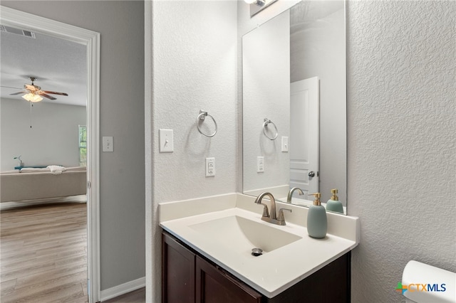 480 Waterloo Dr, Kyle, TX 78640 - bathroom with vanity, ceiling fan, a textured wall, wood finished floors, and toilet
