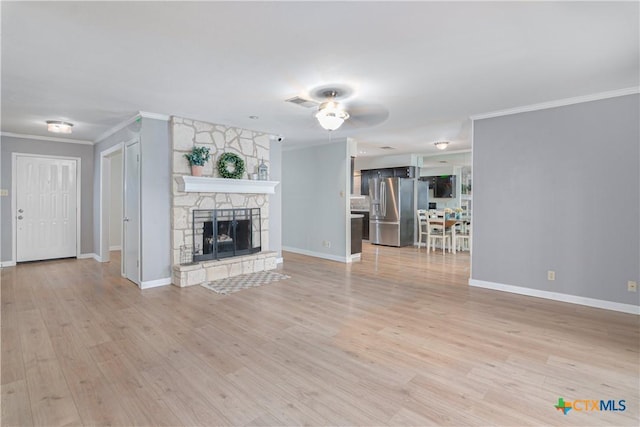 unfurnished living room featuring ornamental molding, light wood-style flooring, a stone fireplace, and baseboards