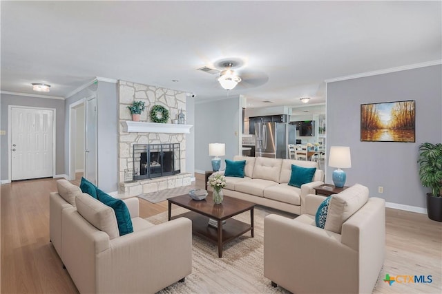 living area with visible vents, baseboards, crown molding, light wood-type flooring, and a fireplace