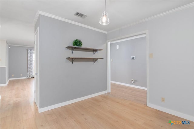 unfurnished room featuring ornamental molding, light wood-style flooring, visible vents, and baseboards