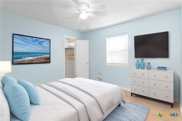 bedroom featuring a textured ceiling, ceiling fan, and light wood-style floors