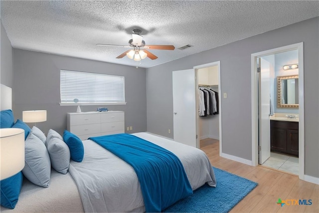 bedroom with visible vents, light wood-style flooring, ceiling fan, a spacious closet, and a closet