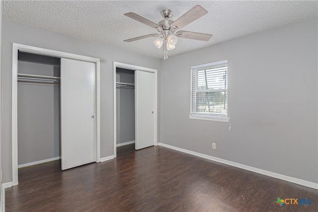 unfurnished bedroom featuring wood finished floors, two closets, and baseboards