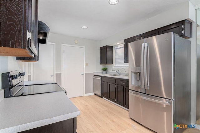 kitchen featuring light wood finished floors, light countertops, appliances with stainless steel finishes, dark brown cabinetry, and a sink