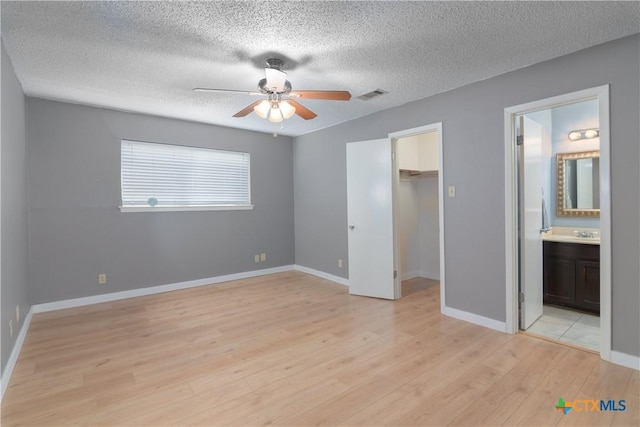 unfurnished bedroom with visible vents, baseboards, a spacious closet, a closet, and light wood-type flooring