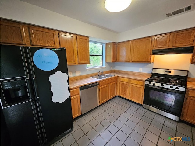 kitchen featuring appliances with stainless steel finishes, light countertops, tile patterned floors, under cabinet range hood, and visible vents