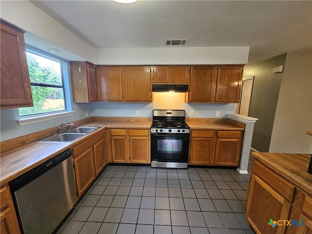 kitchen with visible vents, appliances with stainless steel finishes, a sink, under cabinet range hood, and light tile patterned flooring