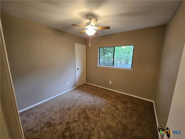 carpeted spare room featuring ceiling fan and baseboards