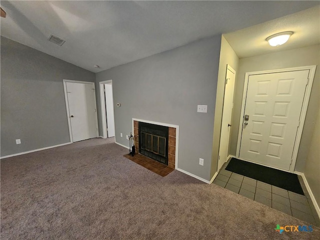 unfurnished living room featuring visible vents, carpet floors, lofted ceiling, and a fireplace