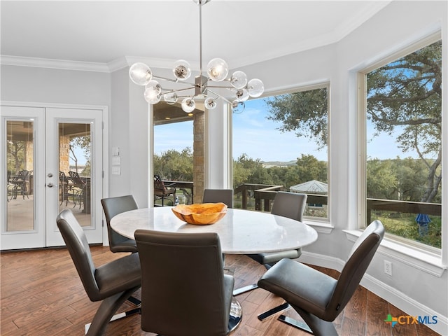 dining room with hardwood / wood-style flooring, a notable chandelier, ornamental molding, and french doors