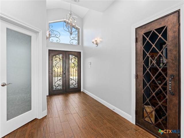 foyer entrance with a chandelier, french doors, dark hardwood / wood-style floors, and vaulted ceiling