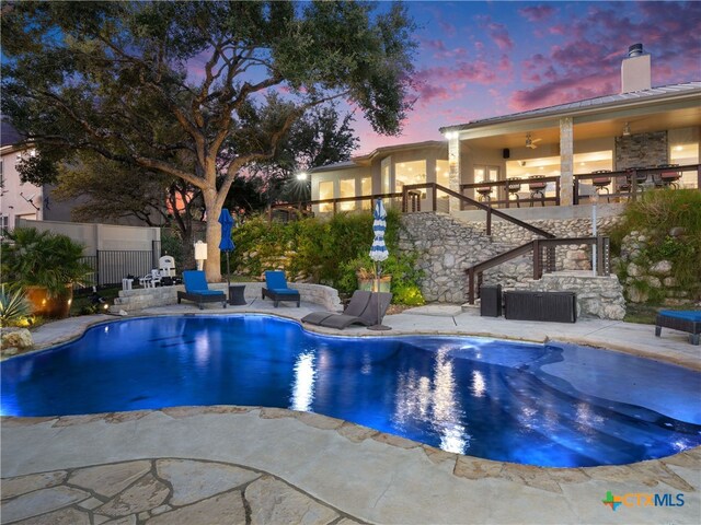 pool at dusk featuring a patio