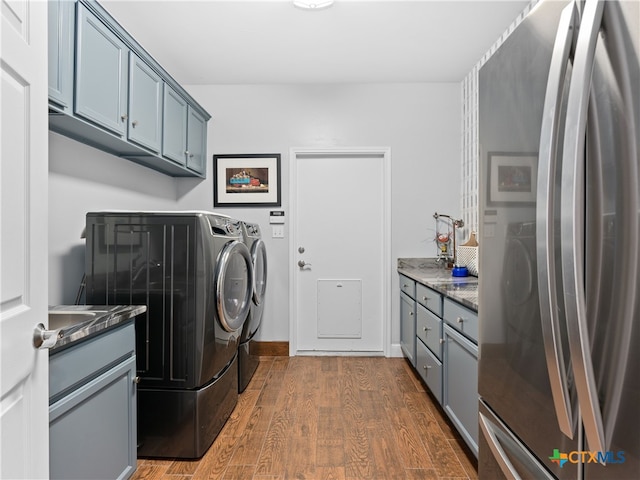 clothes washing area featuring cabinets, dark wood-type flooring, and washing machine and clothes dryer