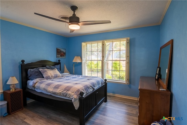 bedroom featuring ceiling fan, a textured ceiling, dark hardwood / wood-style floors, and crown molding