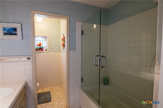 full bathroom featuring tile walls, vanity, combined bath / shower with glass door, and toilet