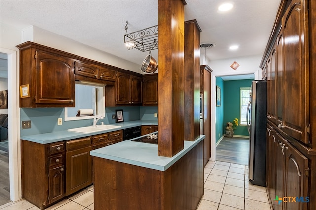 kitchen with a textured ceiling, sink, light tile patterned floors, stainless steel refrigerator, and dark brown cabinets