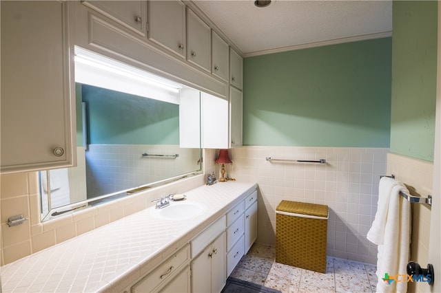 bathroom with vanity, tile walls, a textured ceiling, and ornamental molding