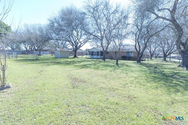 view of yard with driveway, a shed, an outdoor structure, and fence